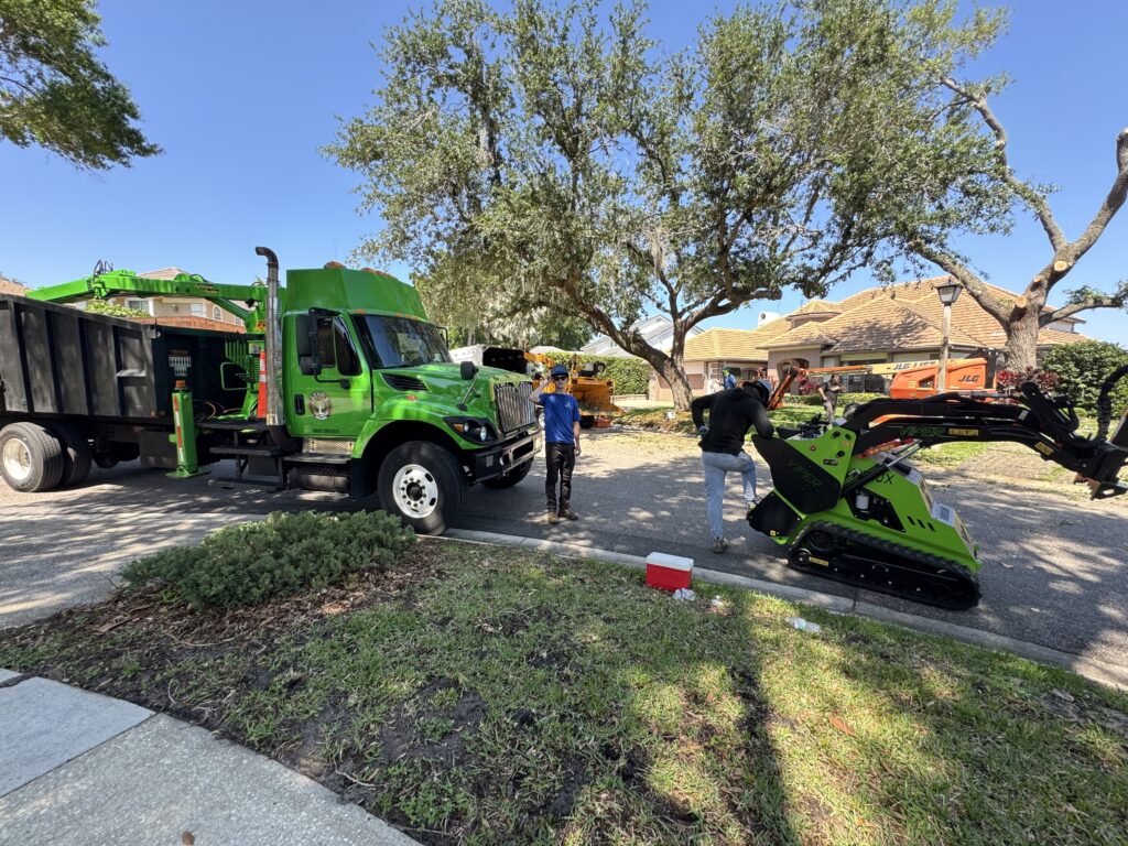 Tree Removal & Trimming in Orlando | Kevin’s Tree Service Kevin’s Tree Service grapple truck on a residential job with a tracked machine moving wood