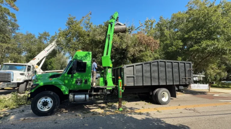 KTS crew member beside the green KTS grapple truck on a crane-assisted removal