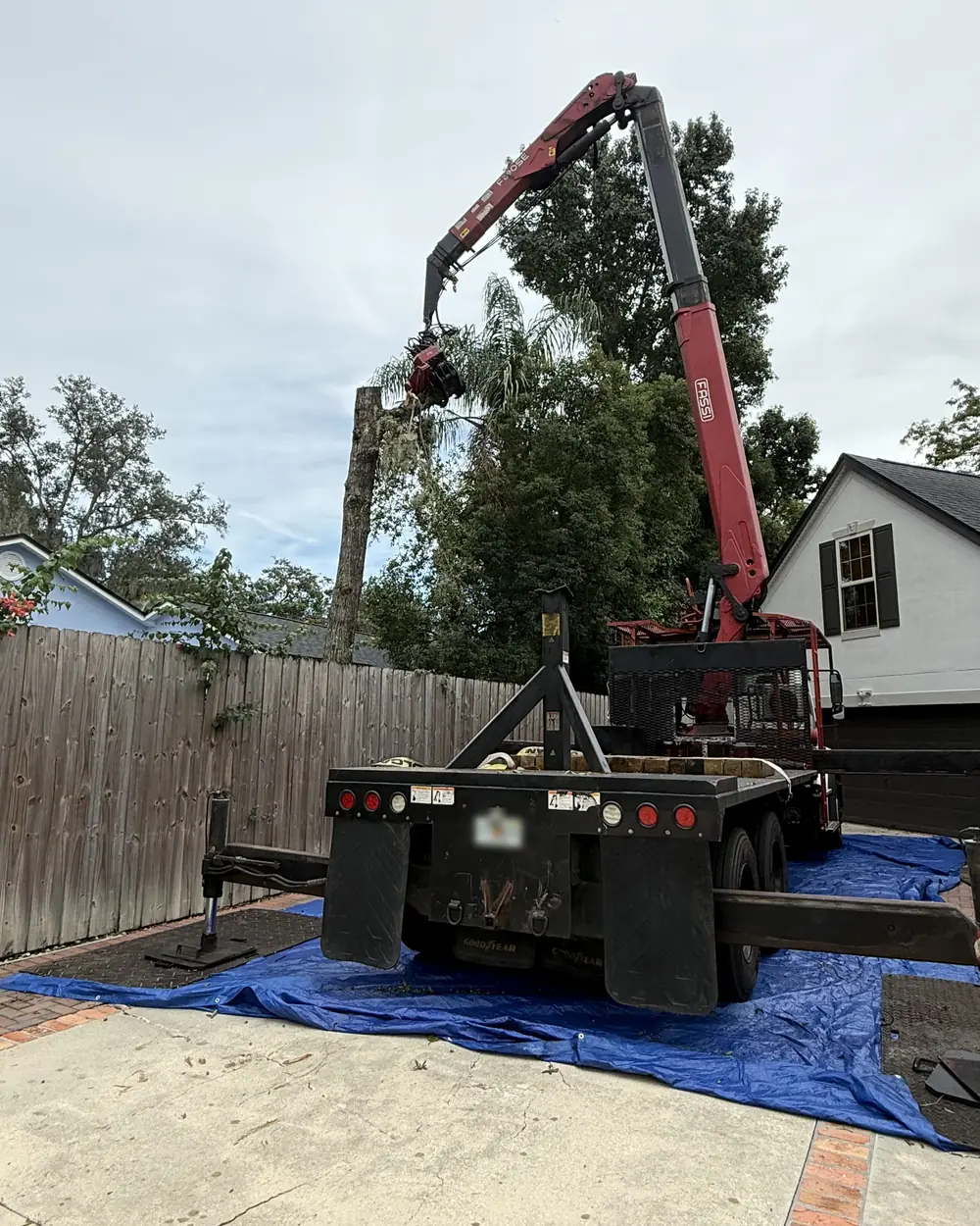 Grapple saw truck set up on tarps and ground mats to protect a residential driveway
