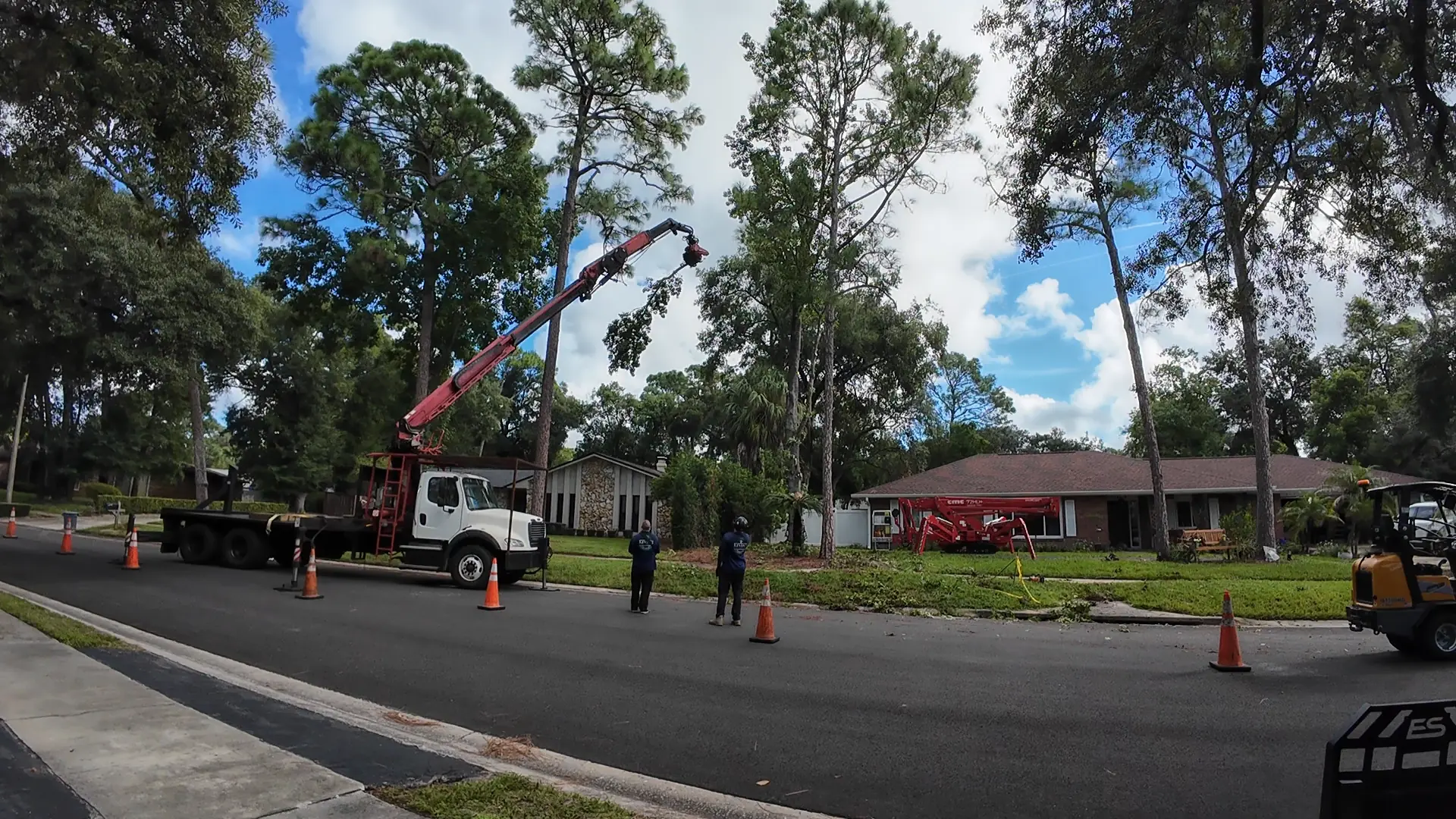 Kevin's Tree Service grapple saw truck lifting a cut limb during a residential tree removal in the Orlando area