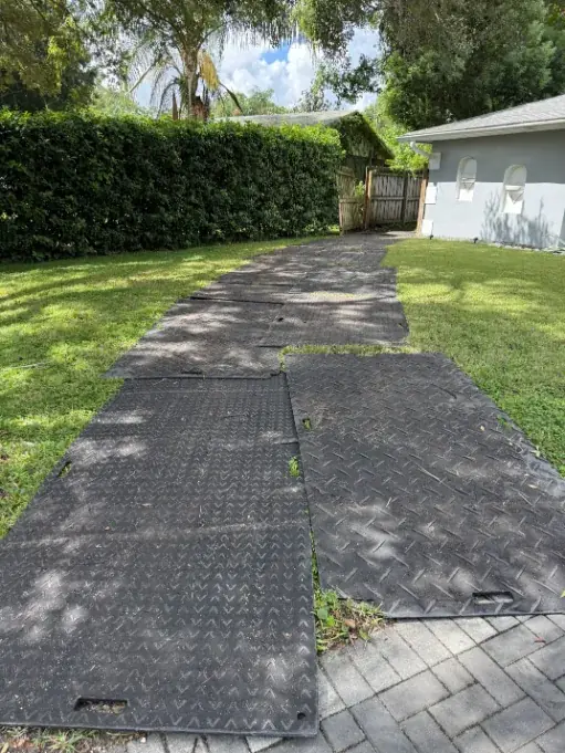 Ground-protection mats laid across a lawn for equipment access